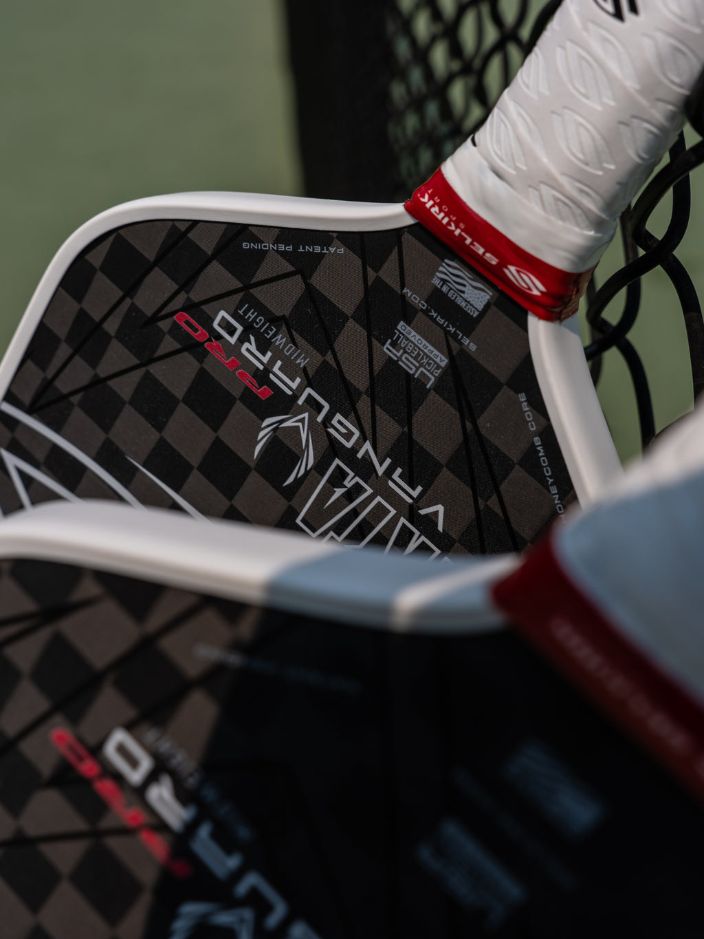 Two black and white paddles with a checkered pattern resting on a fence.