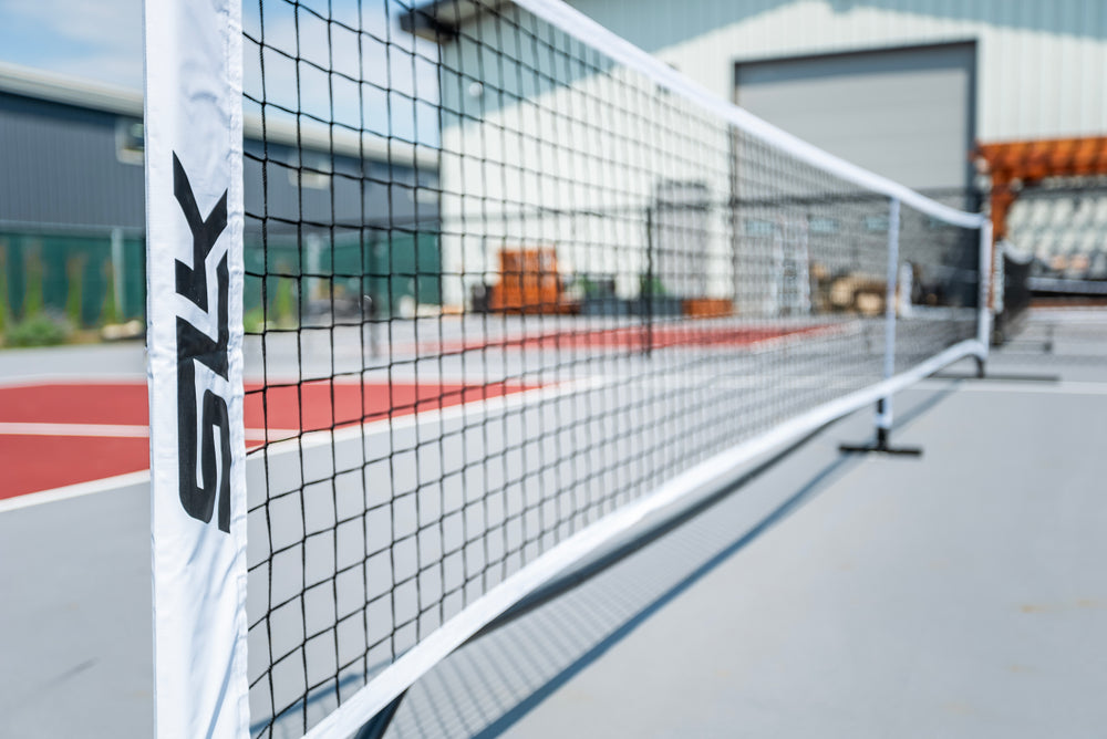 Portable pickleball net set up on a court, featuring a white net with 'SLK' branding.