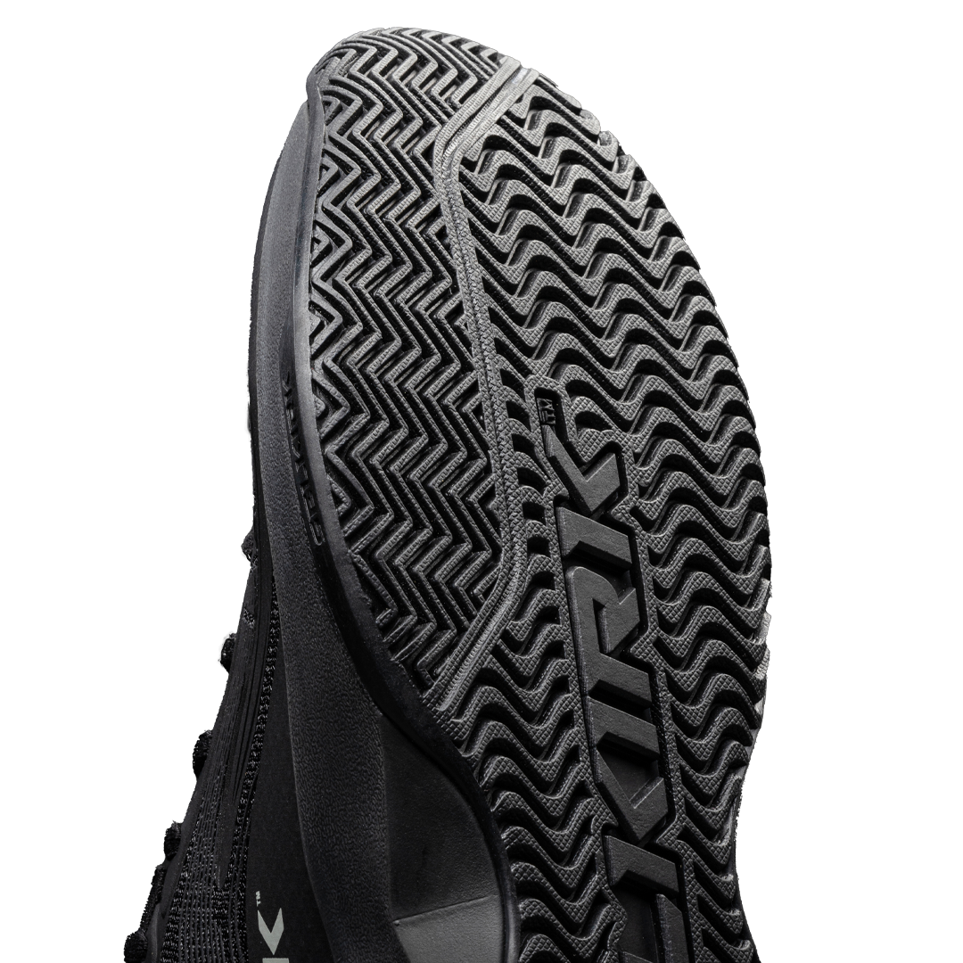 Close-up of the outsole of a black pickleball shoe showing traction pattern and brand name.